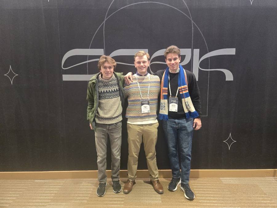 Three students standing in front of the SEEK conference sign