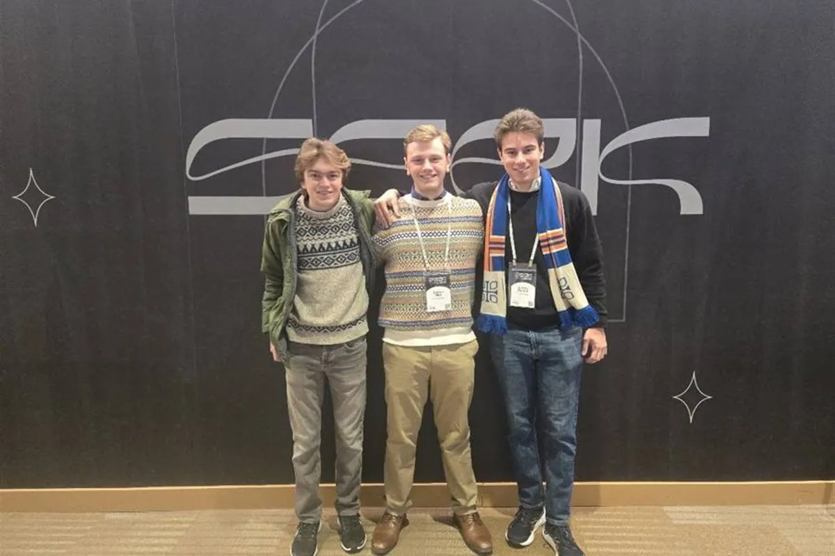 Three students standing in front of the SEEK conference sign